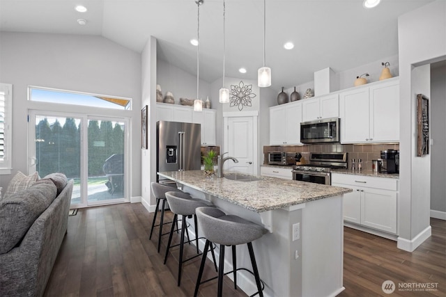 kitchen with a breakfast bar area, stainless steel appliances, dark wood-style flooring, a sink, and backsplash