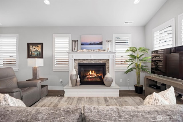 living area featuring baseboards, a stone fireplace, and recessed lighting