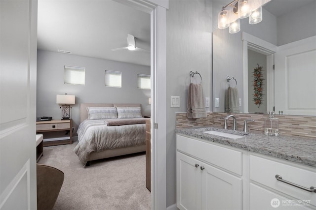 bathroom with tasteful backsplash, vanity, visible vents, and ensuite bathroom