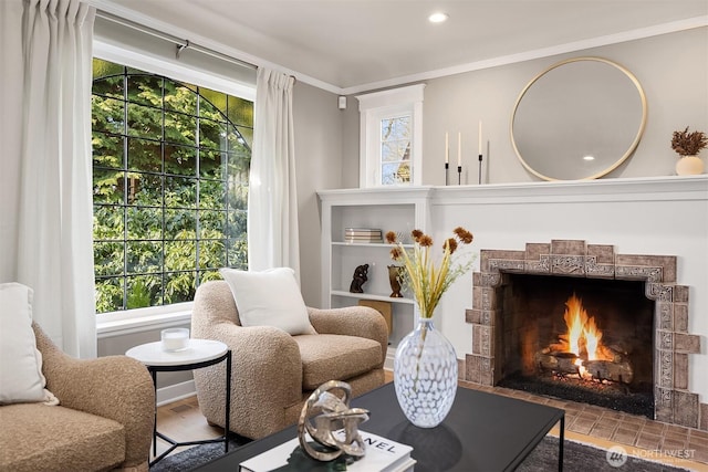 sitting room featuring a tile fireplace, crown molding, and recessed lighting