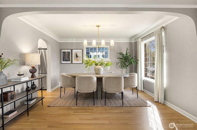 dining space featuring light wood finished floors, baseboards, ornamental molding, and a chandelier