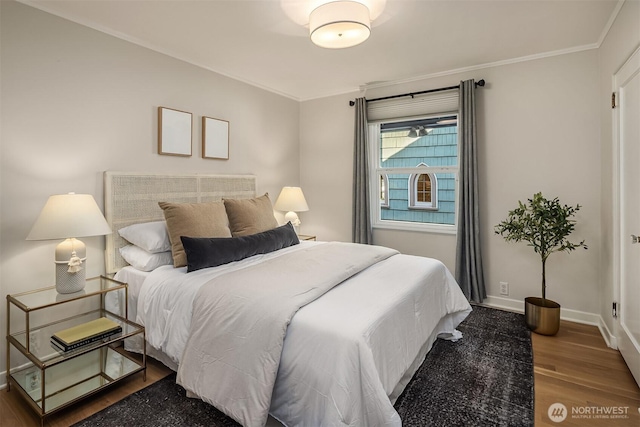 bedroom with crown molding, baseboards, and wood finished floors