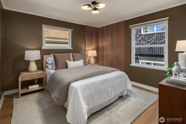 bedroom with ornamental molding, wood finished floors, and baseboards