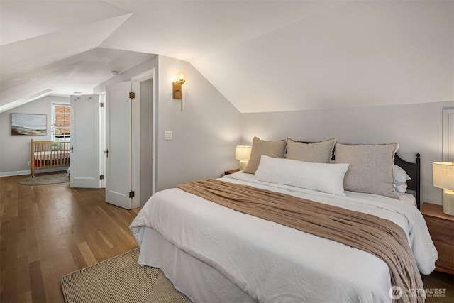 bedroom with lofted ceiling, baseboards, and wood finished floors