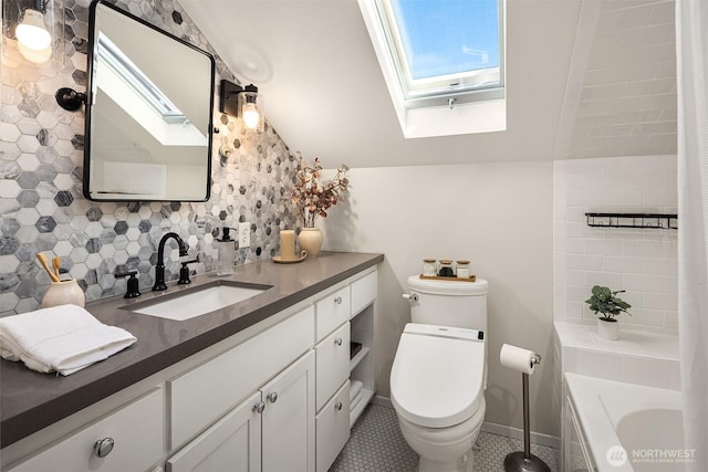 full bath with decorative backsplash, toilet, vanity, vaulted ceiling with skylight, and a bath