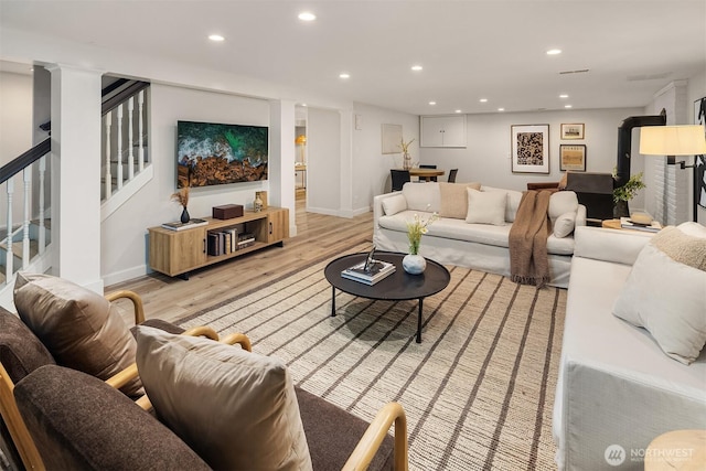 living room with light wood-style floors, baseboards, stairway, and recessed lighting