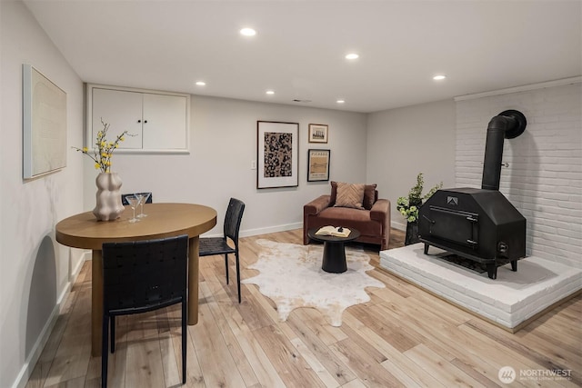 interior space featuring recessed lighting, a wood stove, light wood-style flooring, and baseboards