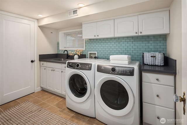 washroom featuring light tile patterned floors, cabinet space, visible vents, a sink, and separate washer and dryer