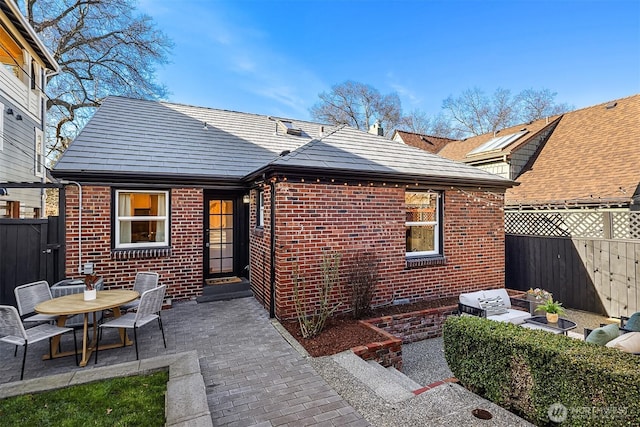 back of house featuring brick siding, a patio, and fence