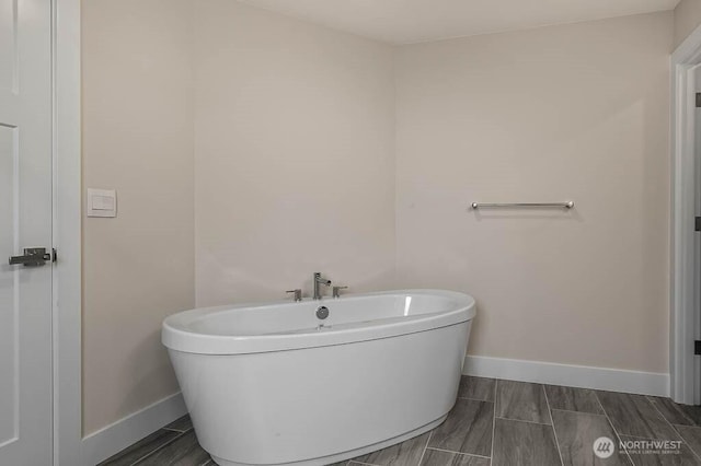 full bath with a freestanding tub and baseboards