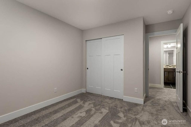 unfurnished bedroom featuring carpet floors, baseboards, and a closet