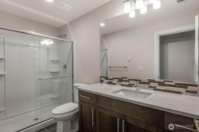 bathroom with tasteful backsplash, visible vents, toilet, a stall shower, and vanity