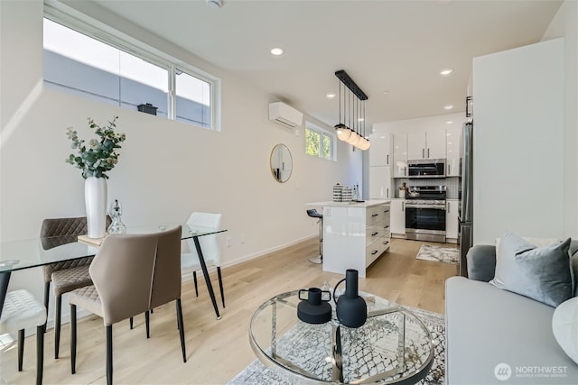 kitchen featuring stainless steel appliances, white cabinetry, an AC wall unit, light countertops, and light wood-type flooring