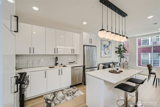 kitchen featuring white cabinets, appliances with stainless steel finishes, light countertops, and a sink