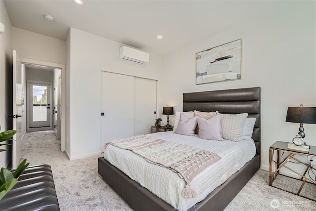 bedroom featuring a closet, carpet flooring, baseboards, and a wall mounted AC