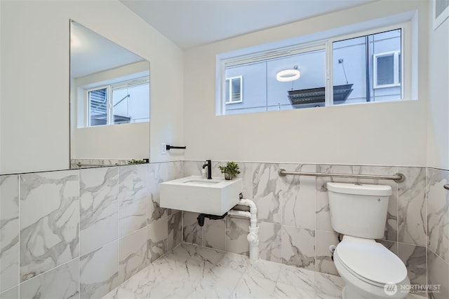 bathroom featuring a wainscoted wall, marble finish floor, a sink, and toilet