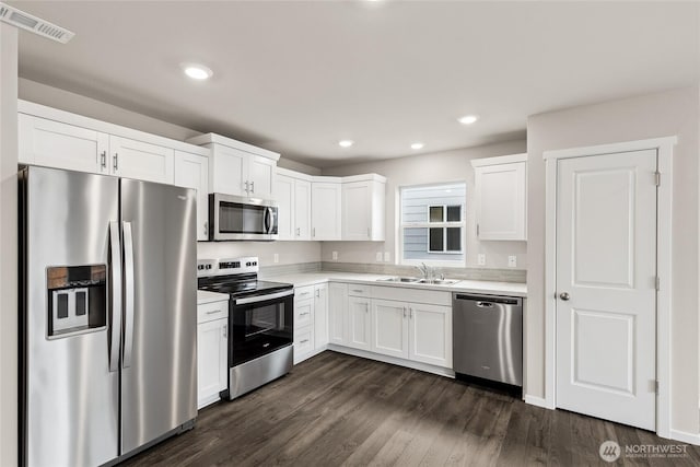 kitchen featuring visible vents, dark wood finished floors, stainless steel appliances, light countertops, and a sink