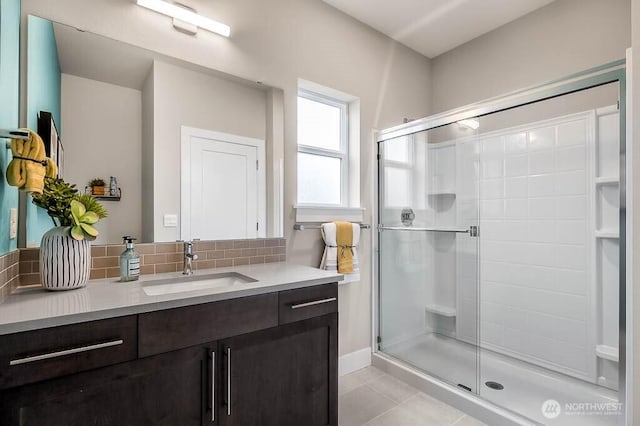 full bathroom with a stall shower, tile patterned floors, vanity, and decorative backsplash