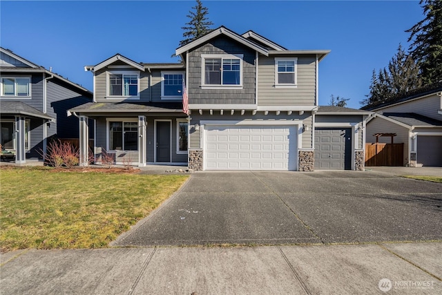 craftsman house featuring stone siding, a porch, concrete driveway, and a front lawn