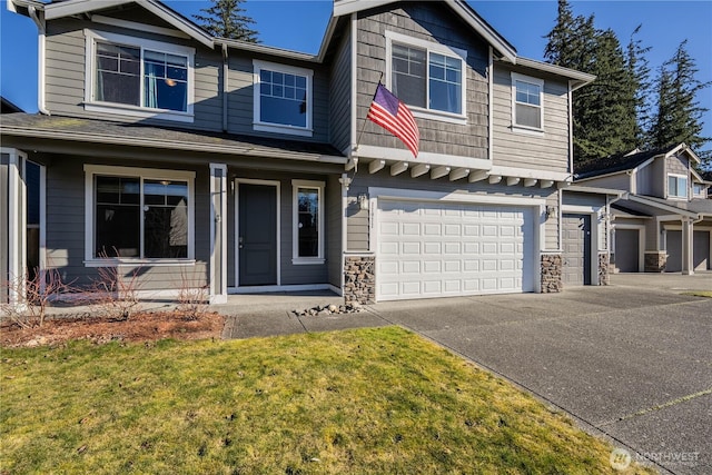 view of front of house with concrete driveway, a front yard, a garage, and stone siding