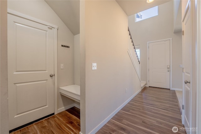 hallway featuring stairs, dark wood-style floors, and baseboards