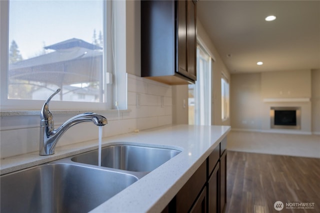 kitchen featuring backsplash, dark wood finished floors, open floor plan, recessed lighting, and a sink