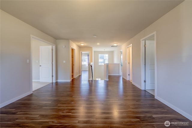 unfurnished room with baseboards and dark wood-type flooring