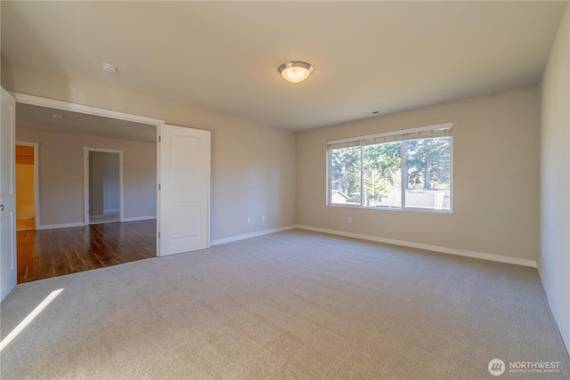 carpeted spare room featuring baseboards