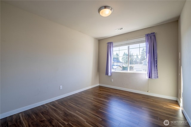 unfurnished room featuring visible vents, baseboards, and dark wood-style flooring