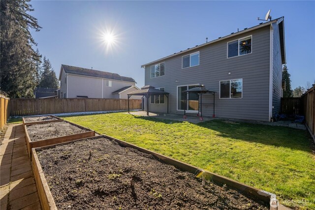 rear view of property with a patio, a garden, a lawn, and a fenced backyard