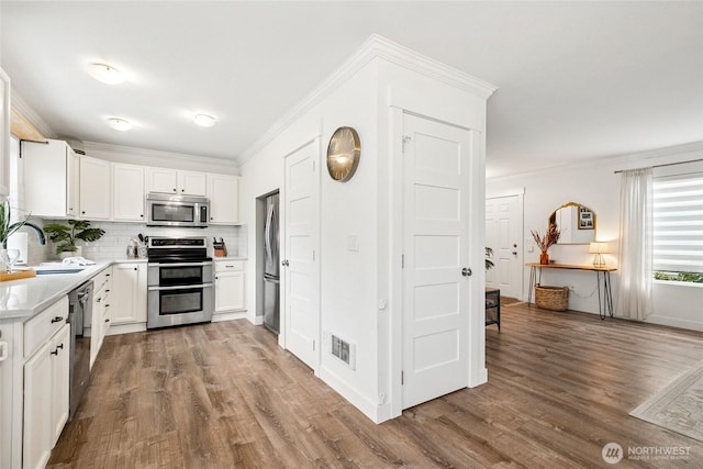 kitchen featuring a sink, visible vents, light countertops, appliances with stainless steel finishes, and crown molding