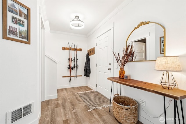 entrance foyer featuring baseboards, visible vents, ornamental molding, and wood finished floors