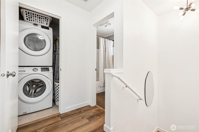 washroom with a chandelier, laundry area, stacked washer / dryer, and wood finished floors