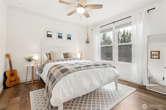 bedroom featuring baseboards, wood finished floors, and crown molding