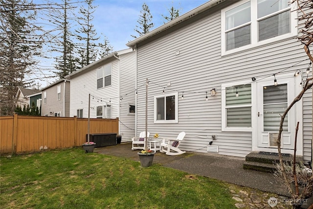 rear view of property with fence, a lawn, and a patio