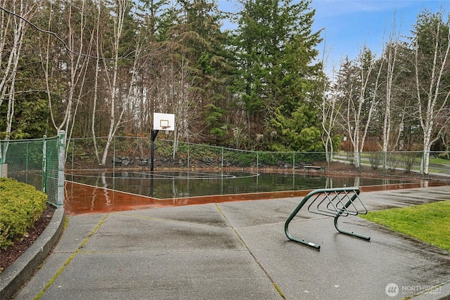 view of basketball court featuring community basketball court, a water view, and fence