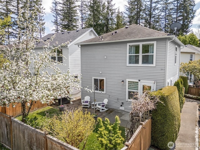 back of property featuring a patio, roof with shingles, and a fenced backyard