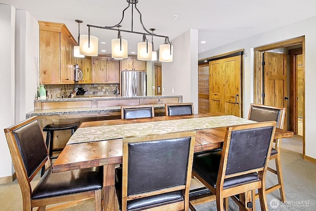 kitchen featuring light colored carpet, decorative light fixtures, a peninsula, stainless steel appliances, and backsplash