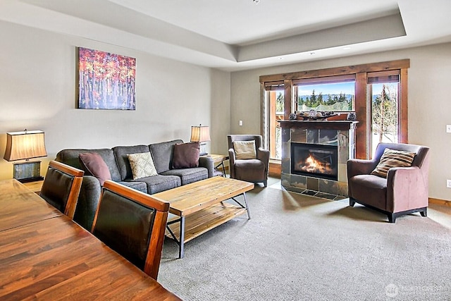 living area featuring a tray ceiling and a tiled fireplace