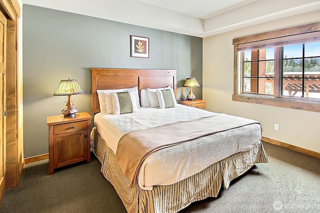 bedroom featuring dark carpet and baseboards