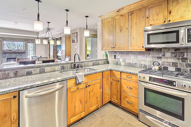 kitchen with light tile patterned floors, light stone counters, stainless steel appliances, a sink, and decorative backsplash