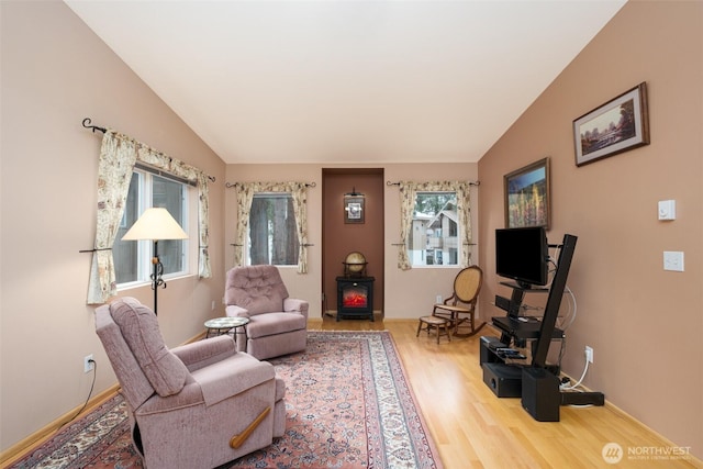 living area with baseboards, wood finished floors, and vaulted ceiling