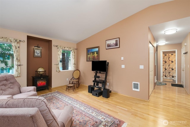 living room featuring vaulted ceiling, wood finished floors, and visible vents