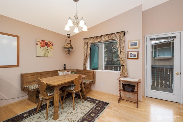 dining area featuring an inviting chandelier, wood finished floors, and vaulted ceiling