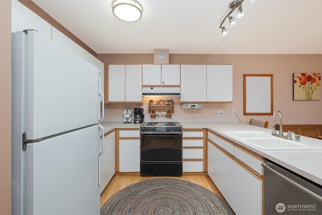 kitchen with a sink, range with electric stovetop, freestanding refrigerator, light countertops, and dishwasher