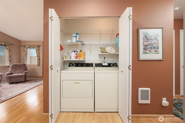 washroom featuring laundry area, light wood-style flooring, heating unit, and separate washer and dryer