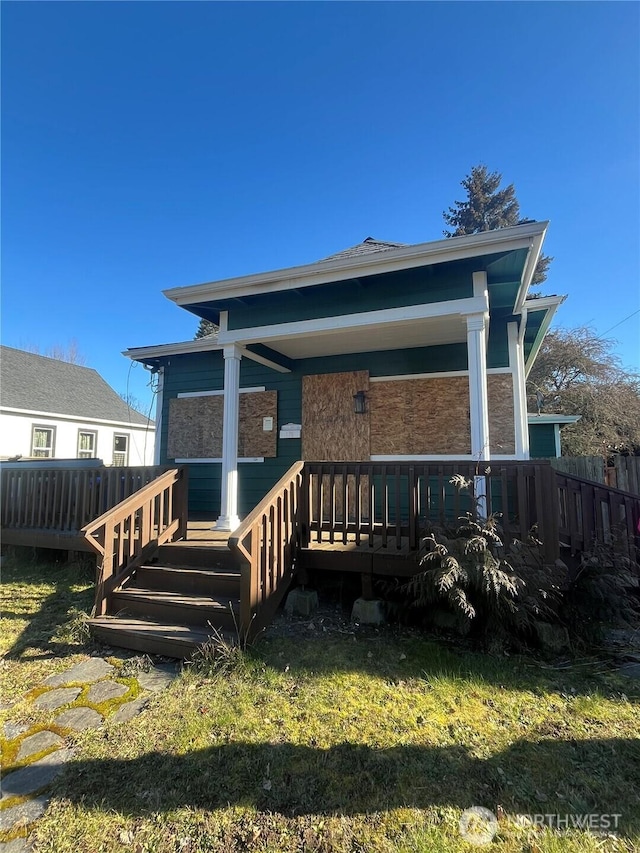 rear view of property featuring a porch and fence