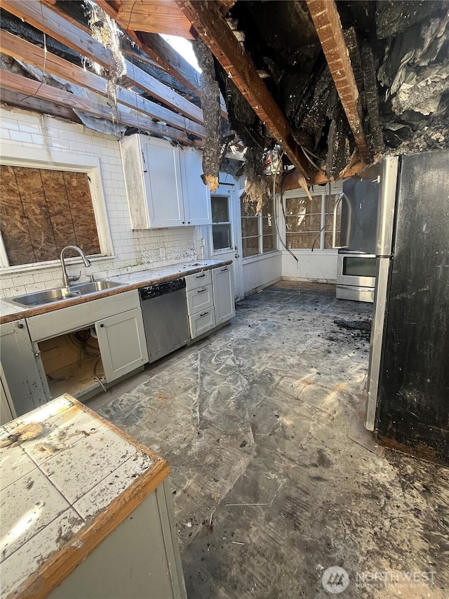 kitchen with stainless steel appliances, light countertops, a sink, and tasteful backsplash