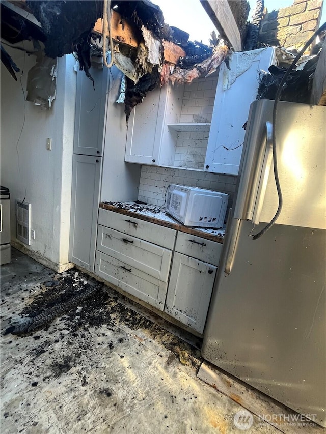 kitchen with white microwave, freestanding refrigerator, and heating unit