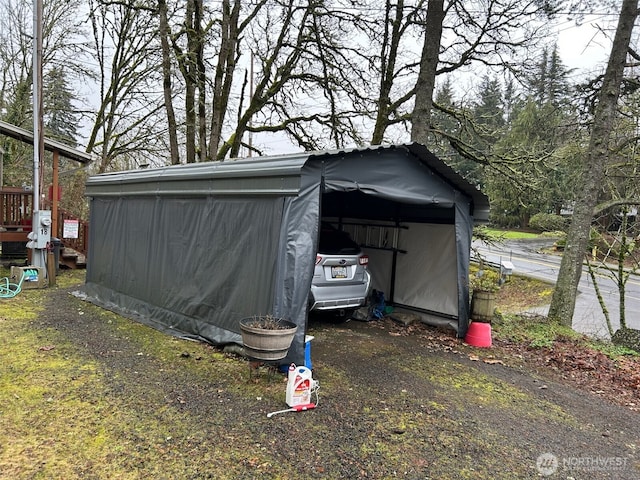 view of outdoor structure featuring a carport, an outdoor structure, and dirt driveway